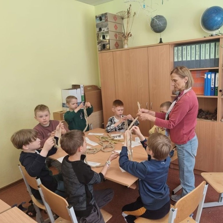 Sākumskolas skolēni kopā ar skolotāju darbojas ar dabas materiāliem klasē